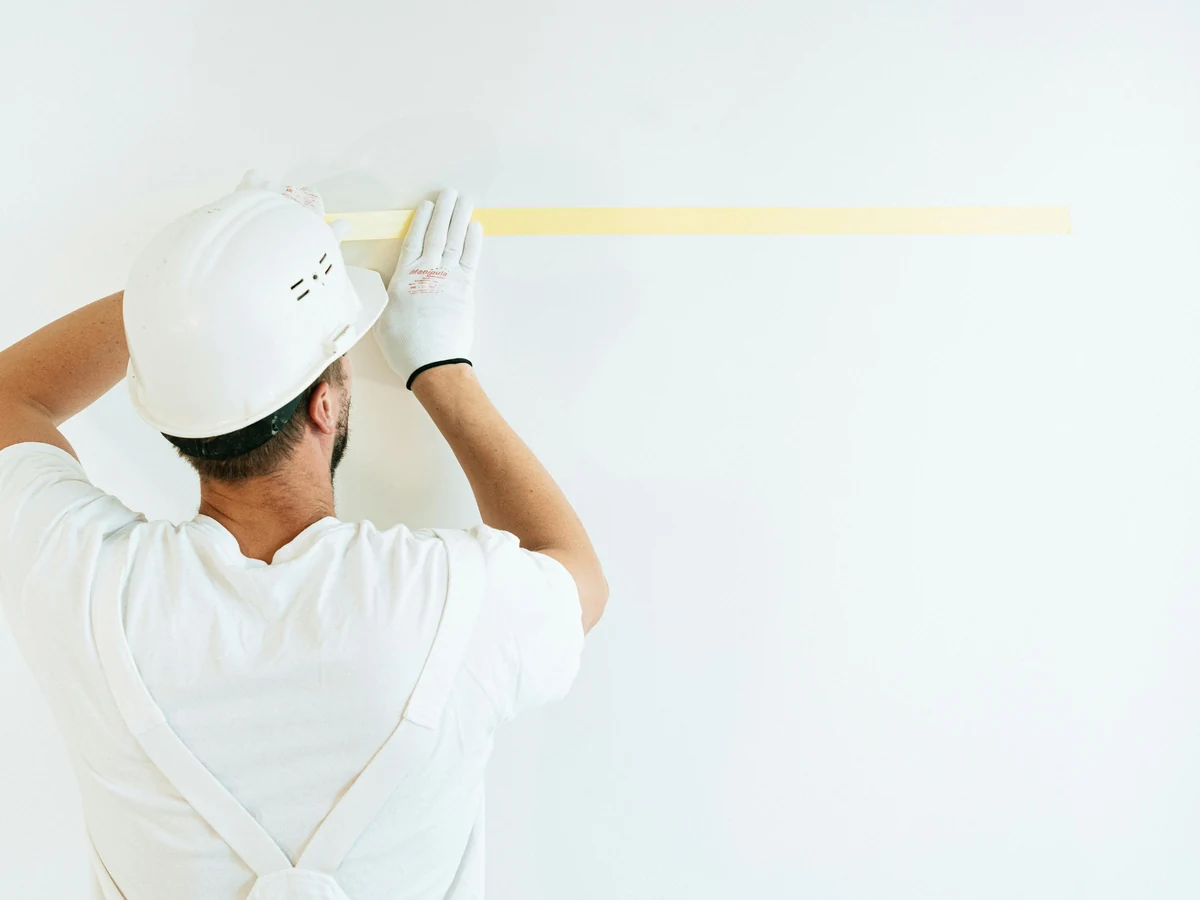 Painter applying masking tape during exterior decorating work by Darlington Decorators