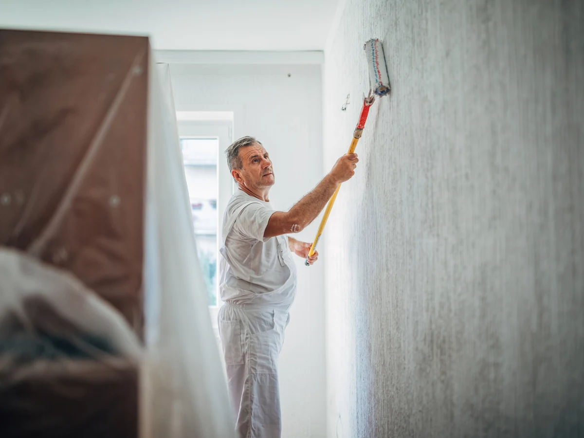 Decorator in white overalls finishing a painting job in Darlington by Darlington Decorators